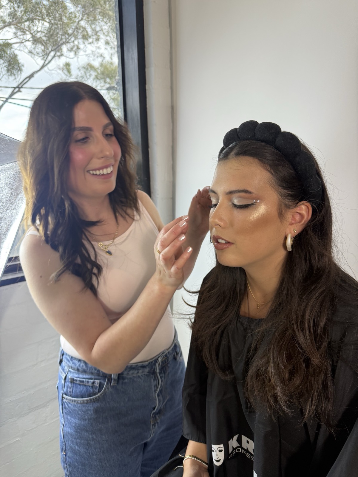 Aphrodite applying eyeshadow to a client during a makeup lesson in Doreen